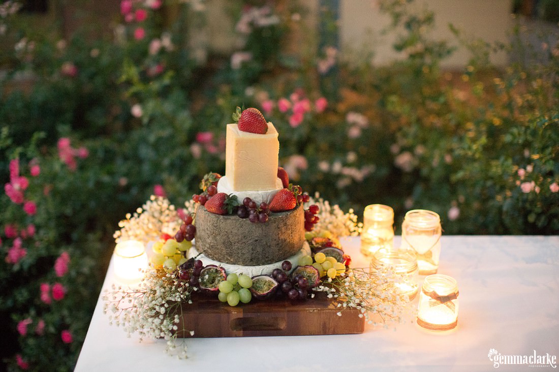 A four tiered cheese "cake" adorned with fruit - Backyard Wedding