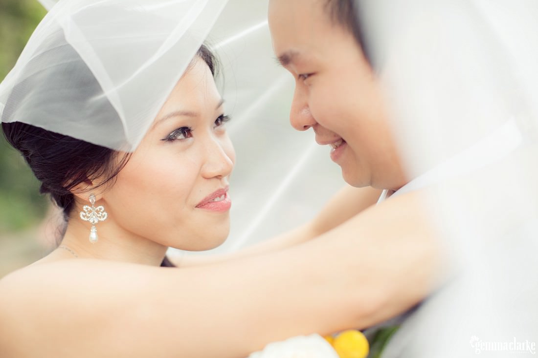 A bride and groom hold each other close underneath the bride's veil - Secret Garden Wedding