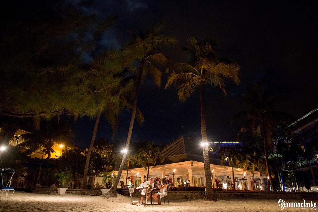 Bride and groom sitting at a table at night by themselves on the beach - an intimate dinner setting at this Caribbean Elopement
