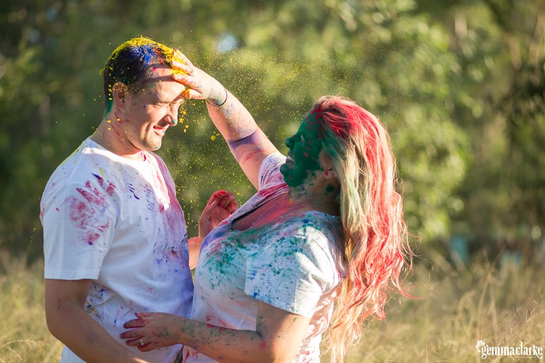 A couple having a colour powder "fight" in a grassy field - Colour Powder Photoshoot