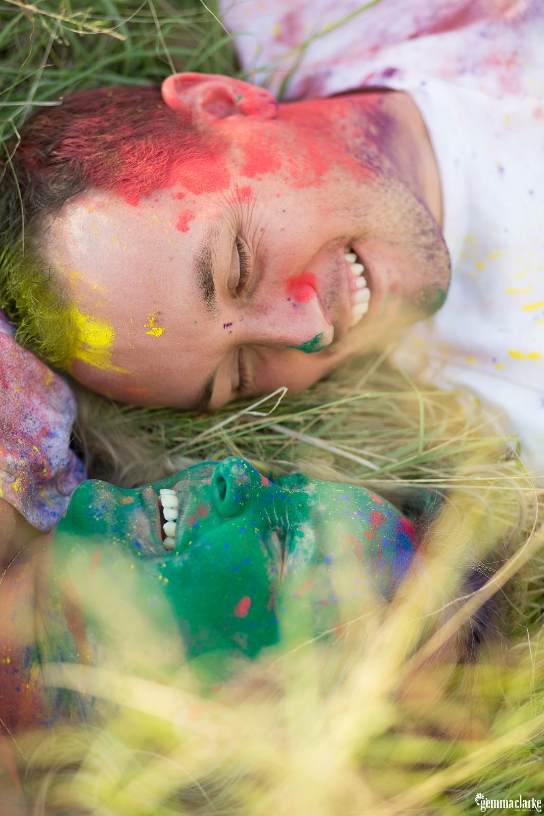 A man and woman laying in the grass with their faces covered in coloured powder - Colour Powder Photoshoot
