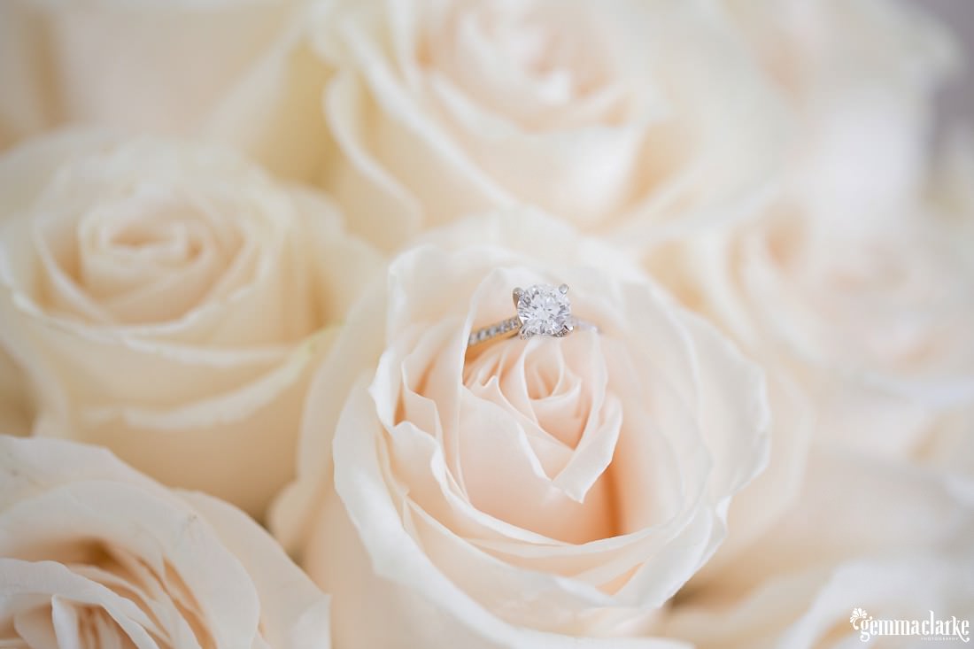 A bride's engagement ring sitting on top of a flower in her bouquet - Horizons Wedding
