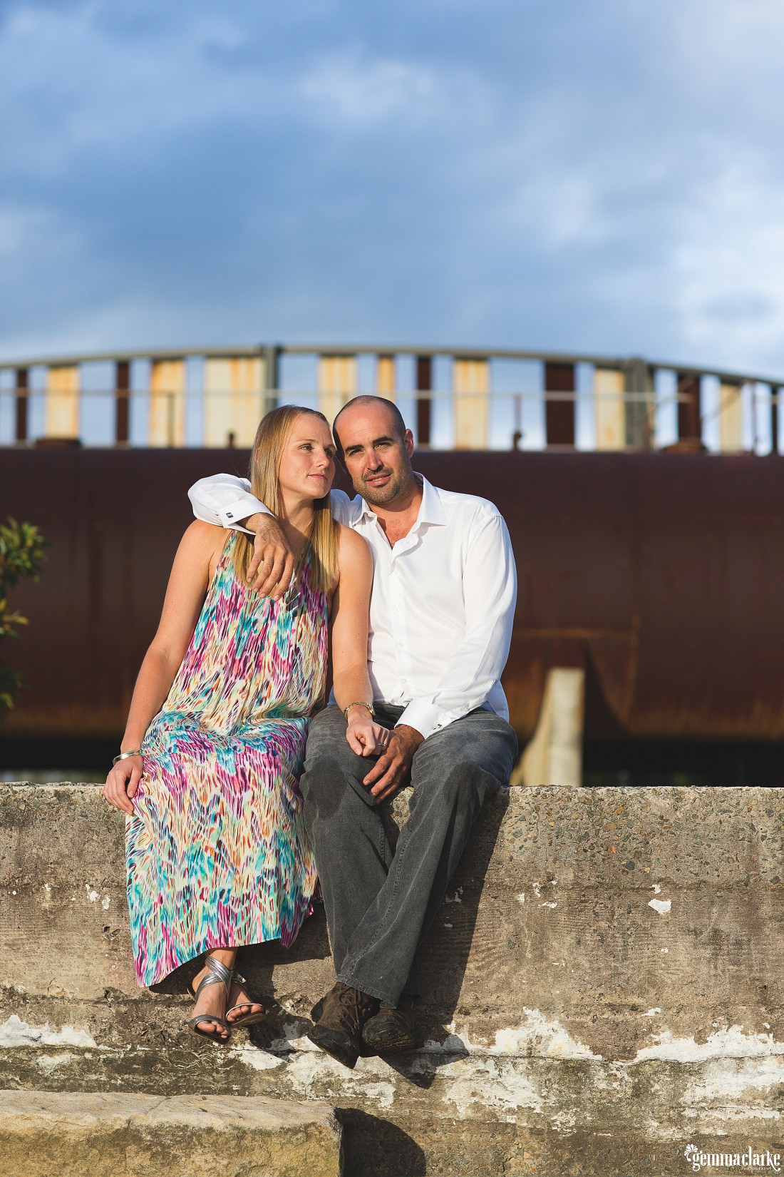 A man and woman sitting together on a concrete wall in the early morning sun - Ballast Point Park Portraits