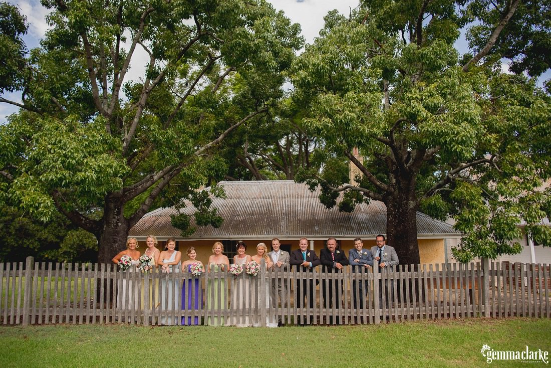 A bridal party posing behind a wooden picket fence - Dairy Precinct Wedding