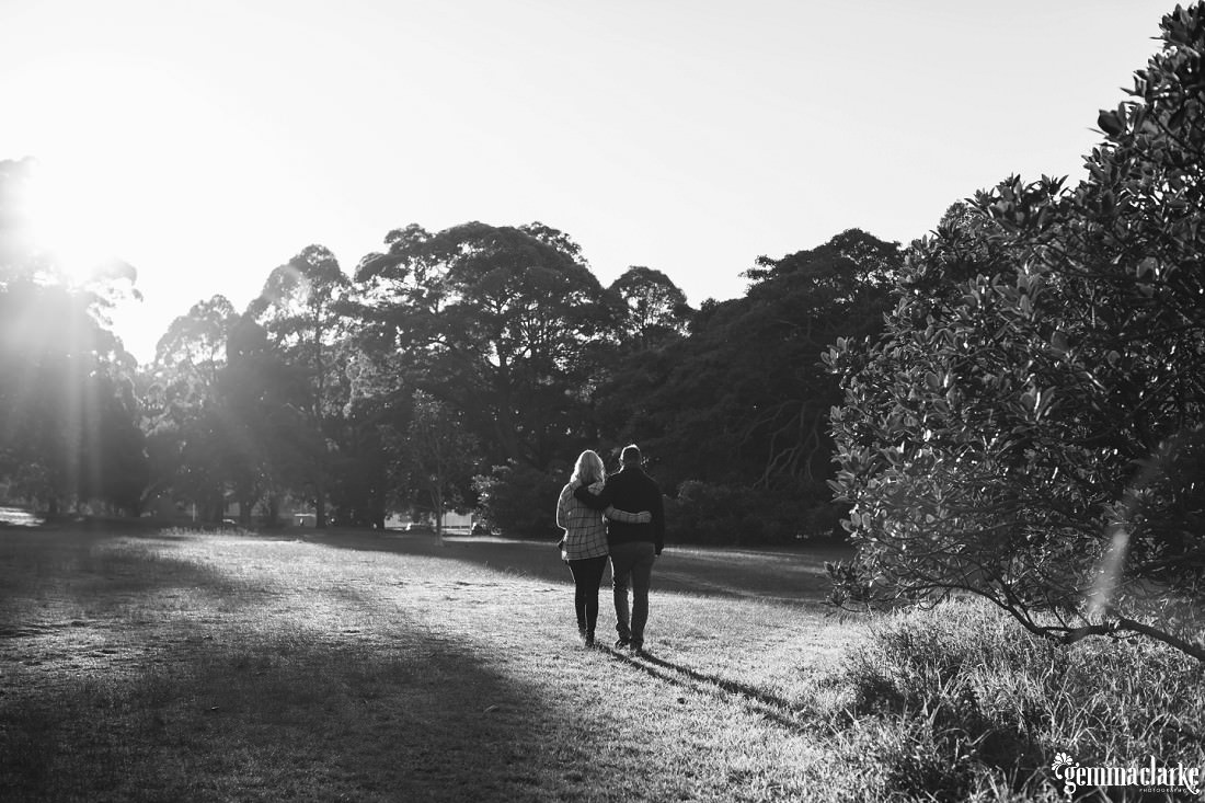 A man and woman walking through a park with their arms around each other