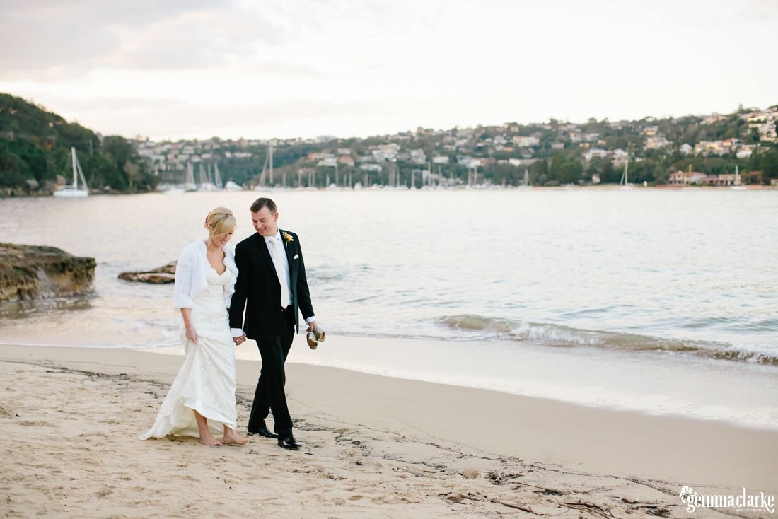 A bride and groom walking hand-in-hand along a beach - Zest at the Spit
