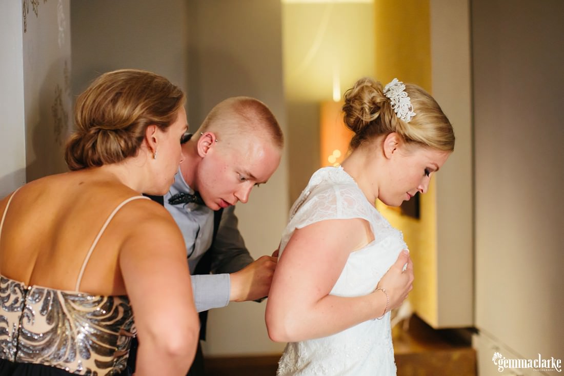 A bride having their back of her dress fastened