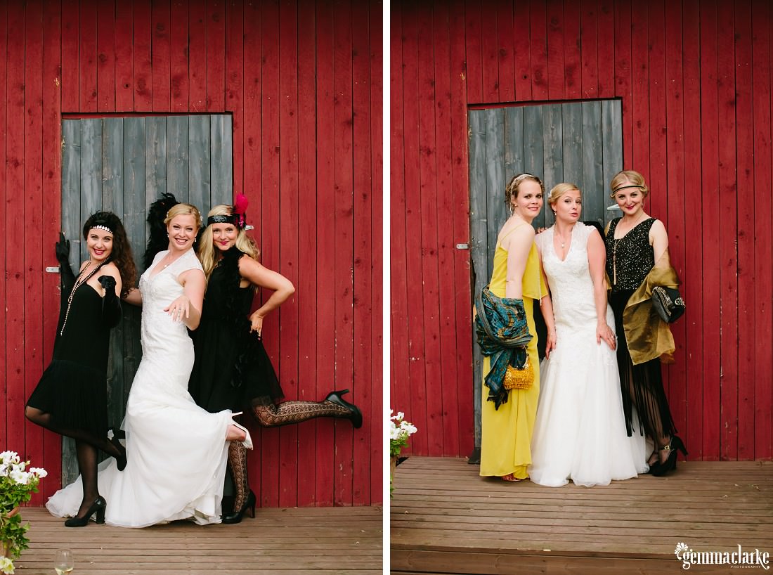 A bride posing with some of her guests in front of a red wooden building