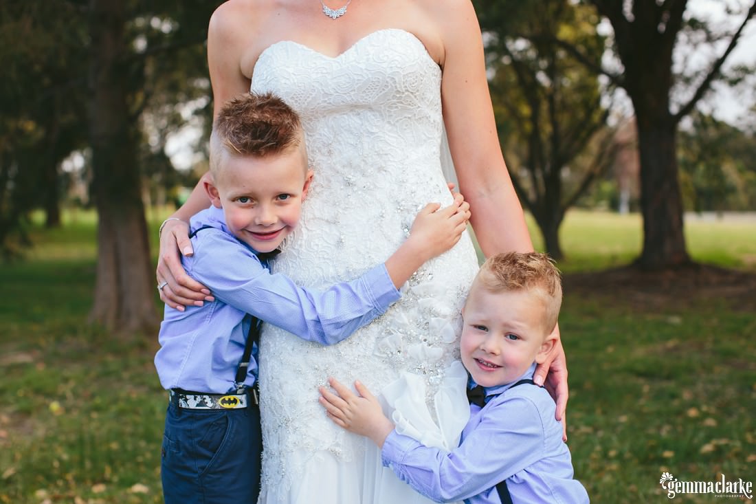A bride getting hugs from two young boys