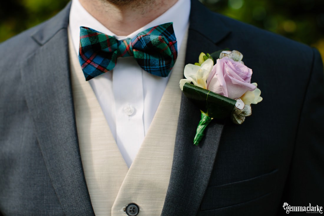 A close up of a groom's accessories and floral buttonhole