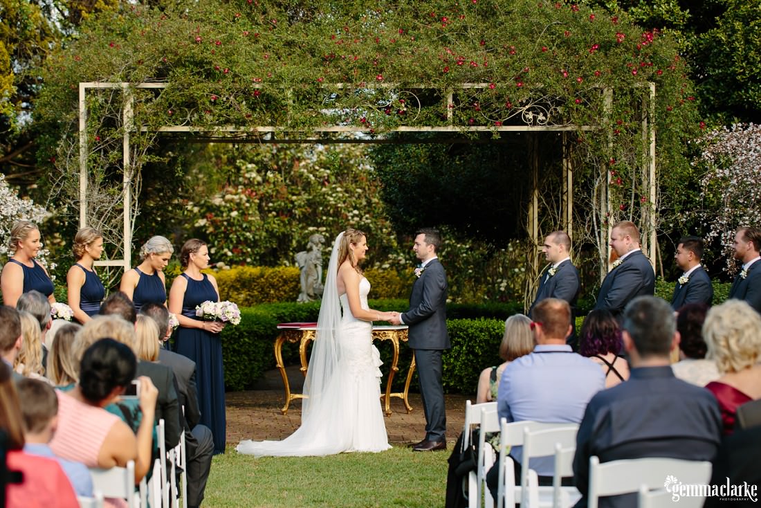 A bride and groom holding hands as their wedding guests look on