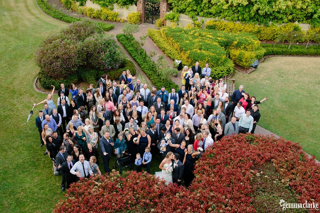An overhead shot of a wedding party and guests on a lawn