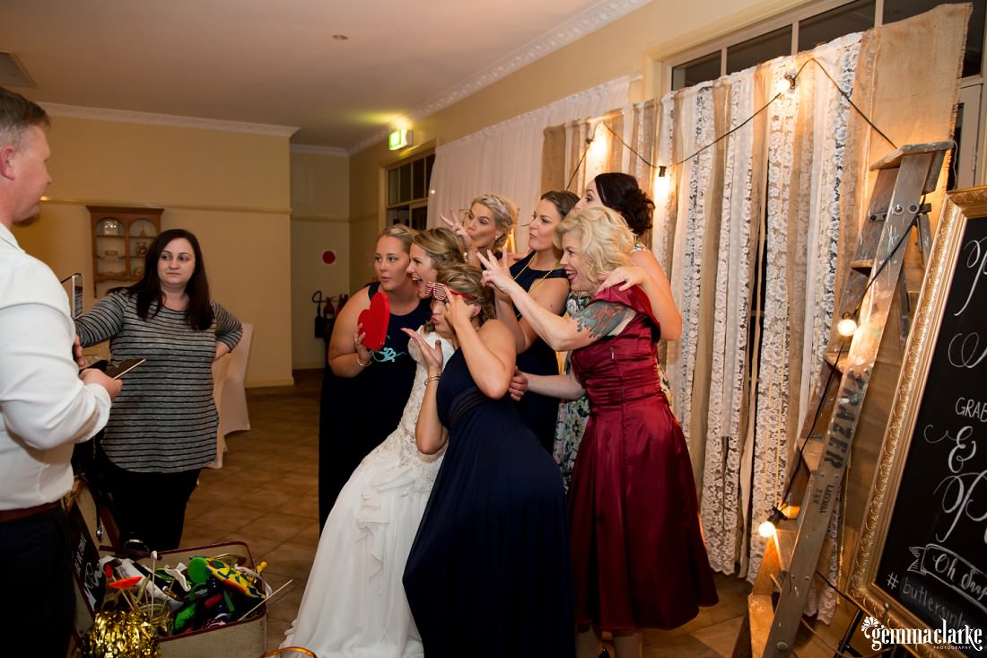 A bride, her bridesmaids and some other guests in a photo booth