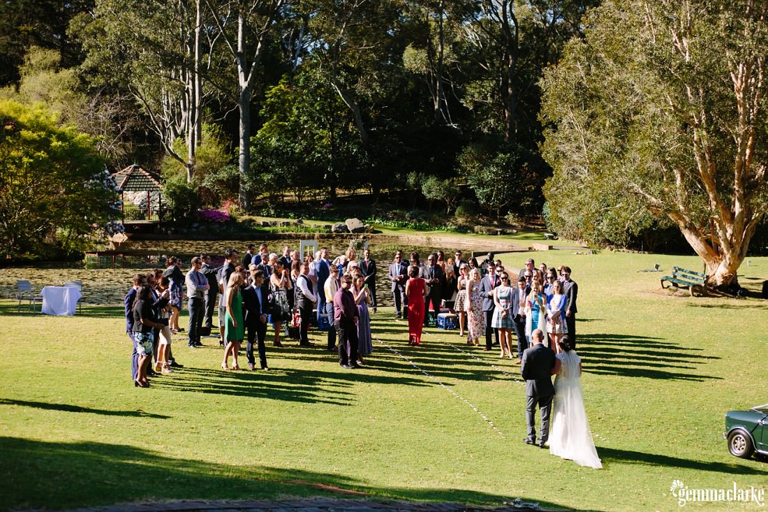 Wedding guests standing as the bride approaches with her father