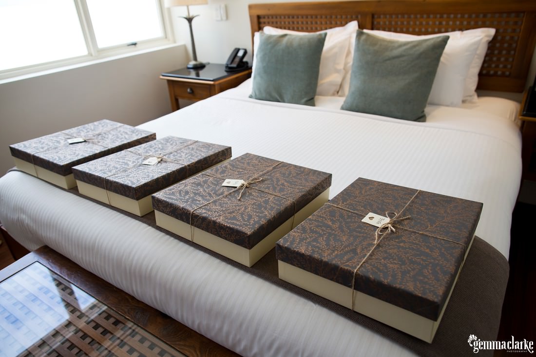 Four gift boxes lined up on the end of a bed