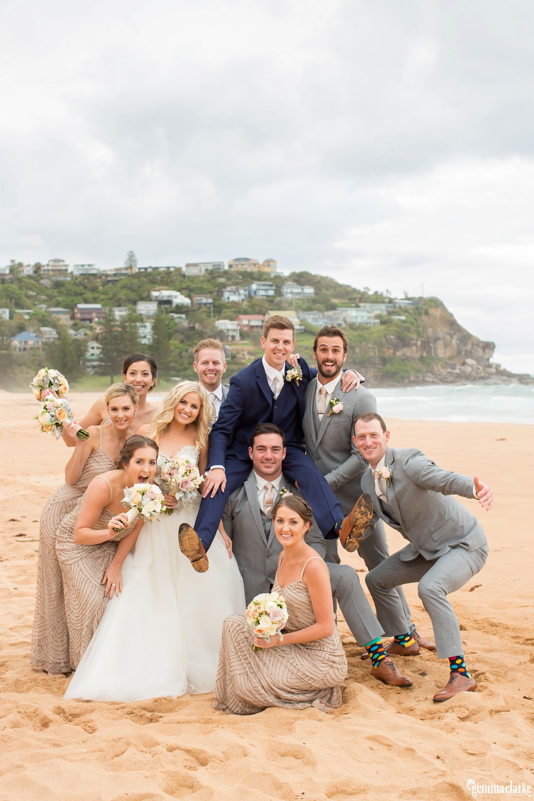 A wedding party posing together on Whale Beach, the groom sitting on the shoulders of his best man