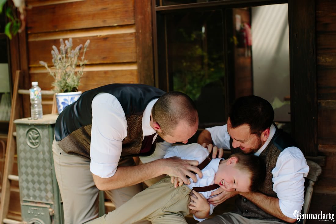 A groom and his best man tickle the groom's young son