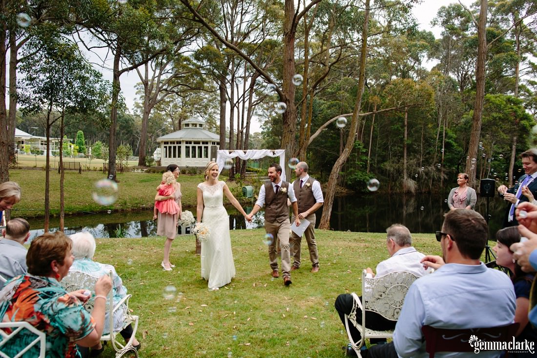Bubbles in the air as a bride and groom walk back down the aisle after being married