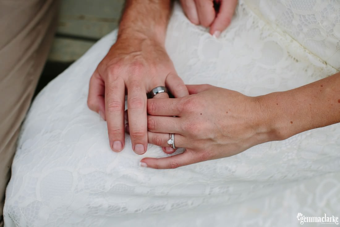 A closeup of a bride and groom holding hands