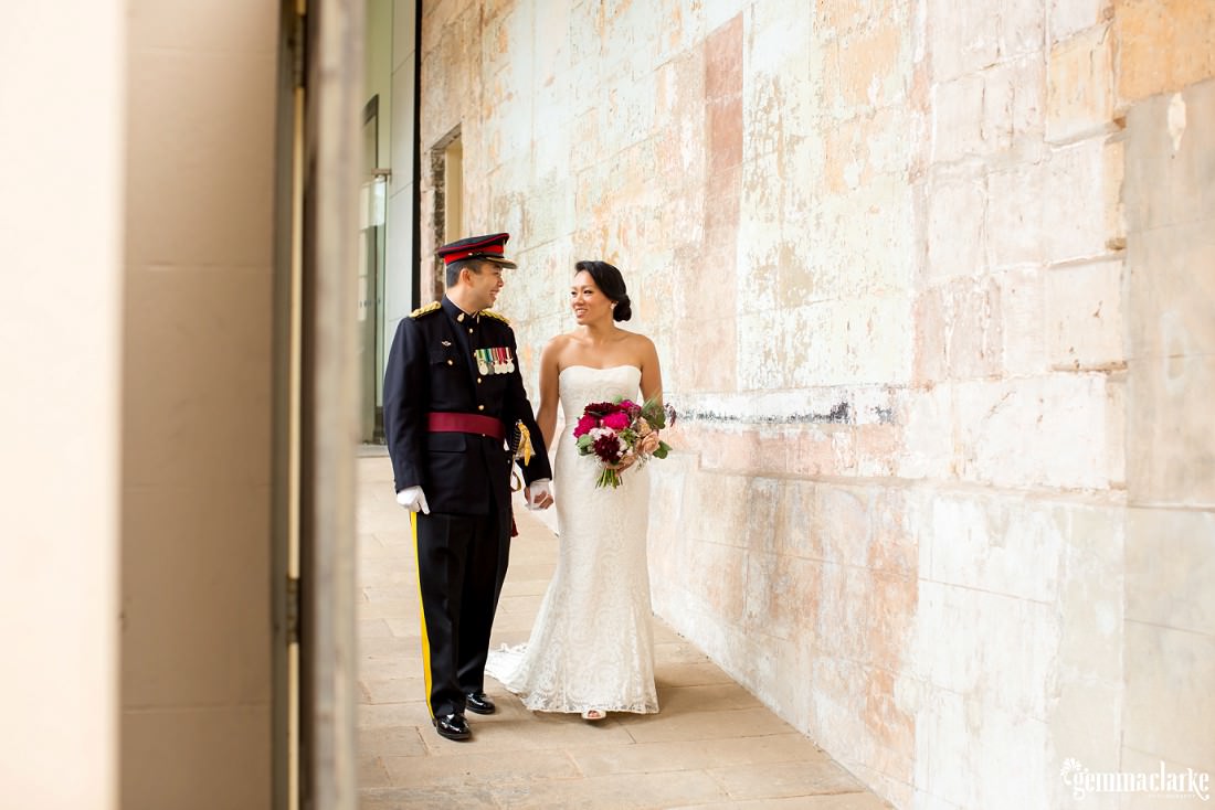 A bride and groom looking into each others eyes, smiling and holding hands as they walk down a ramp