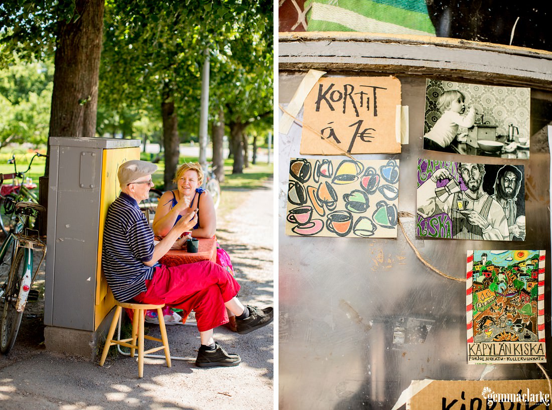 A woman sitting at a table with a man smoking a cigar and some artwork for sale