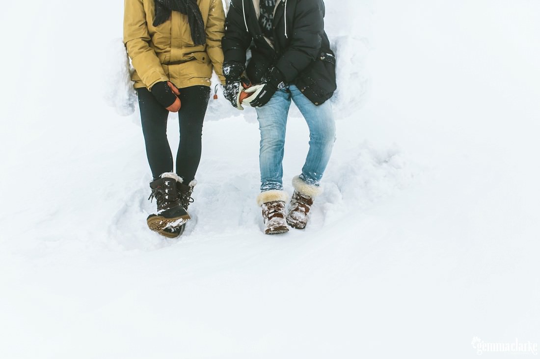 A closeup of a couple holding hands while sitting on a snow covered ski lift
