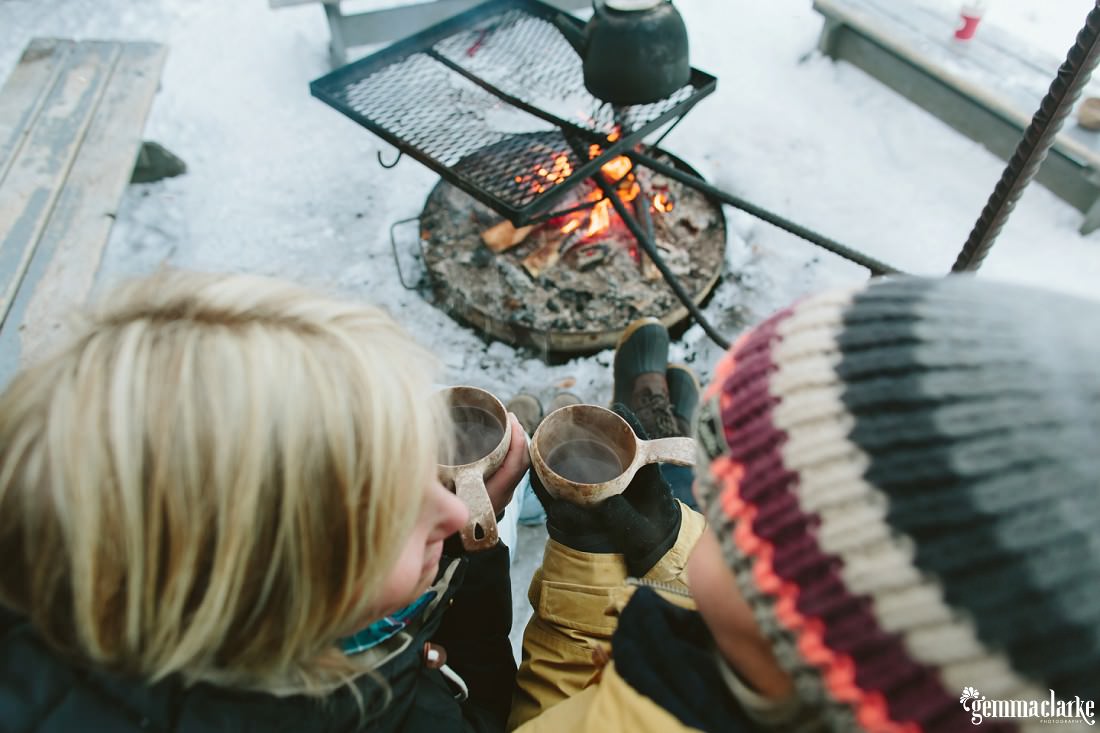 A couple drinking tea in front of an open fire