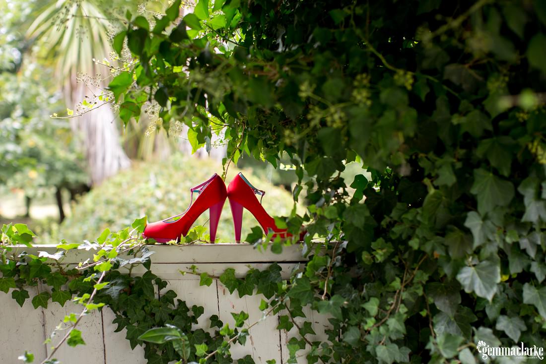 Red high heeled shoes on top of a fence