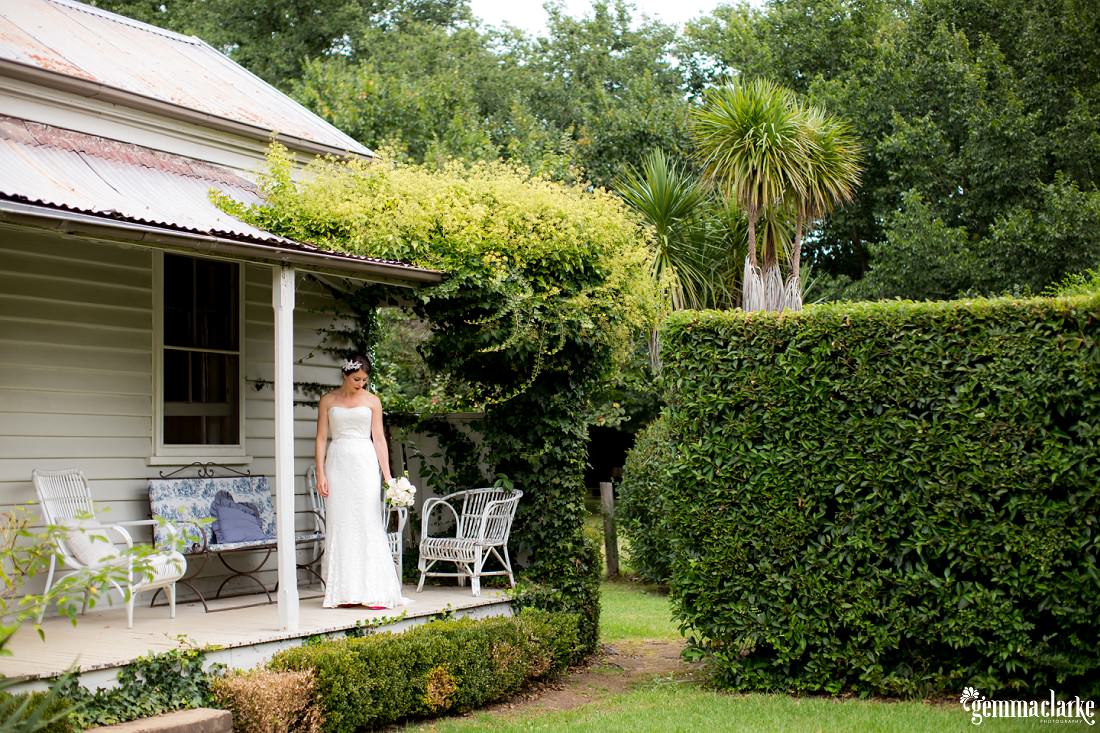 A bride standing on the verandah of a house looking at the garden