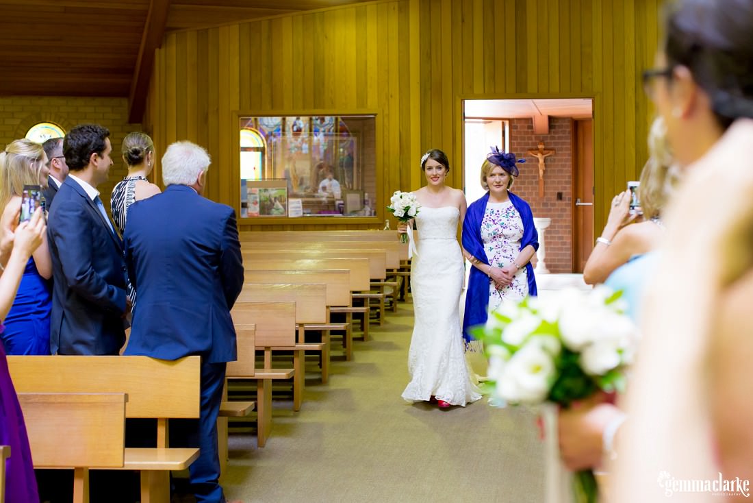 A bride being walked down the aisle of a church by her mother