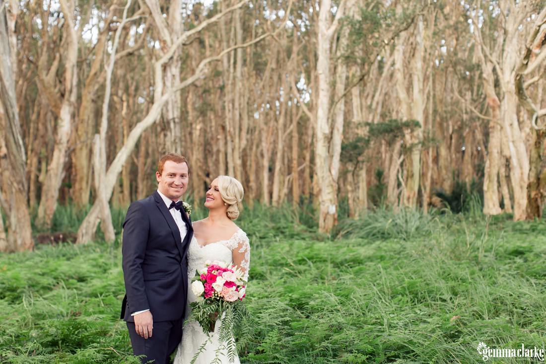 A bride and groom standing together in a forest - Centennial Park Wedding