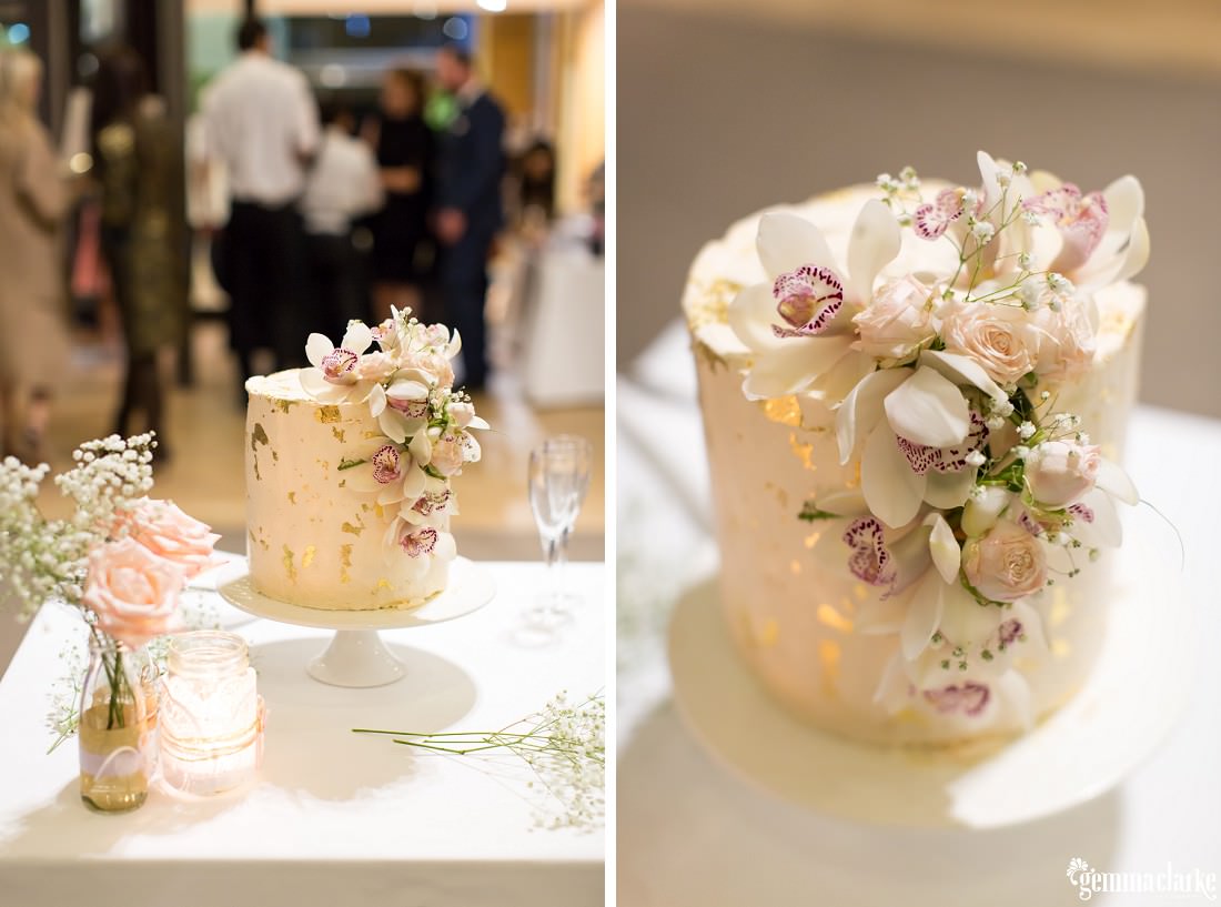 A naked wedding cake with floral decorations and gold flecks