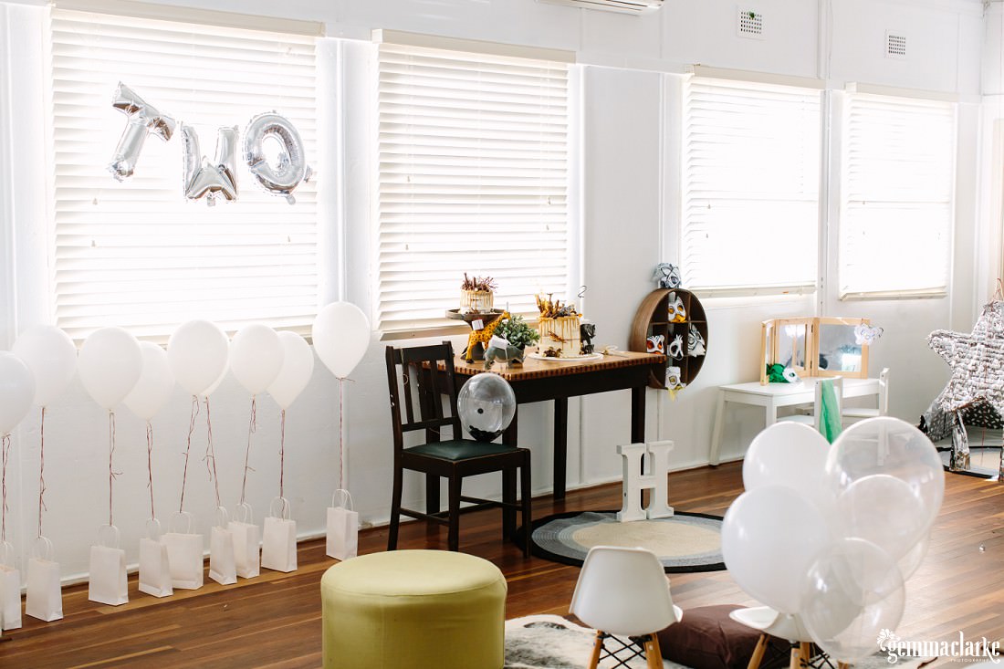 A photo of the room with the goody bags lined up, all with floating balloons attached and then letter balloons above them that spell out the word TWO.