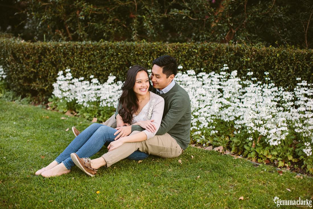 A man and woman sitting together in a garden - Botanic Gardens Engagement Photos