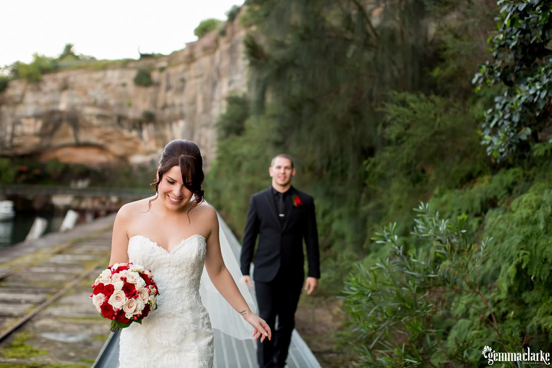 Bride walking in the foreground with the groom following her behind with big cliffs and a railway line in the background at this Deckhouse Wedding