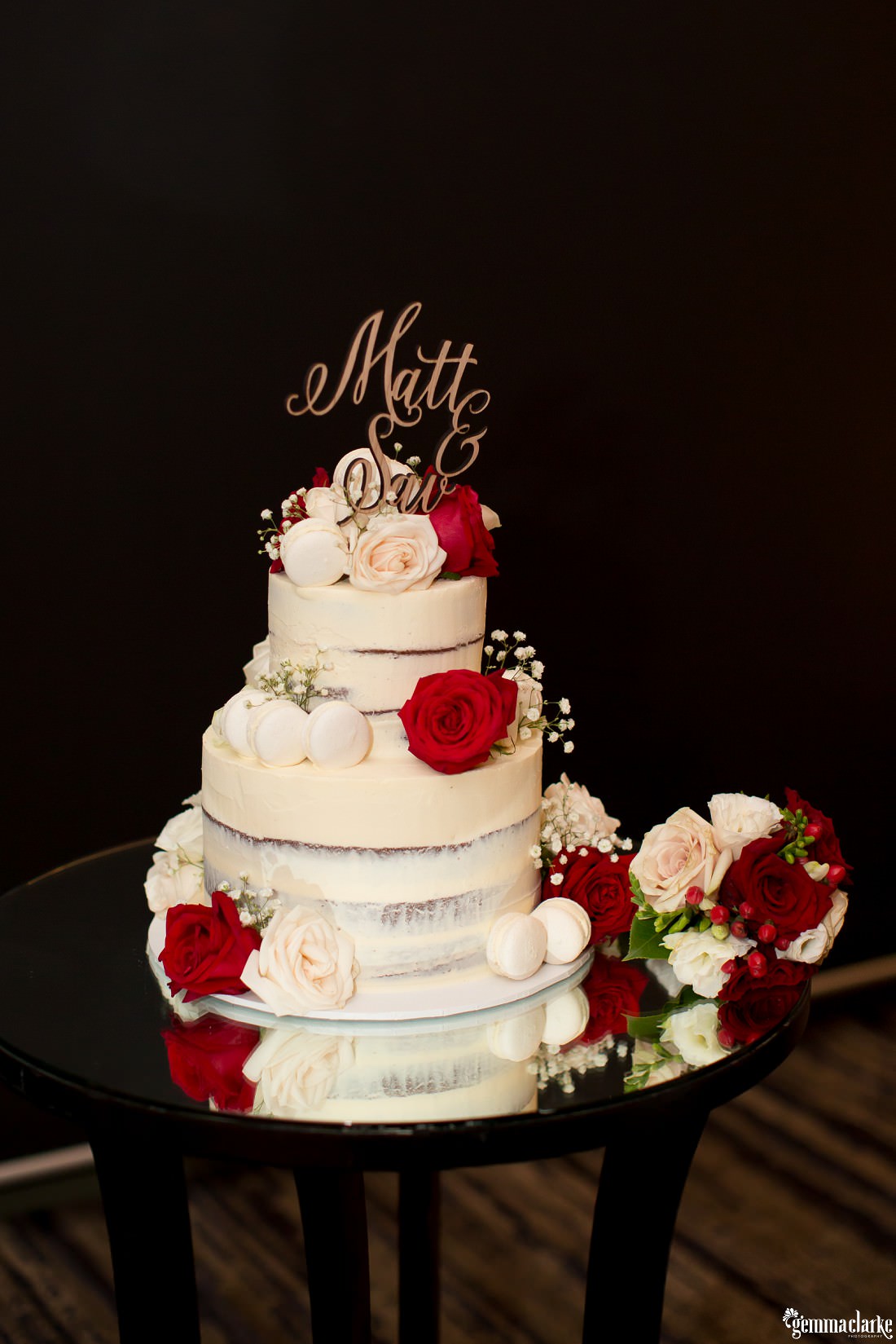 A two tiered naked cake with white and deep red roses - Deckhouse Wedding