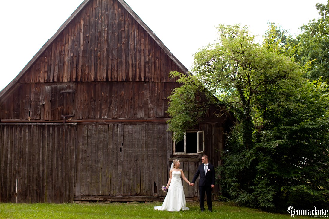 German Country Wedding with Bride and Groom holding hands in front of a big brown barn