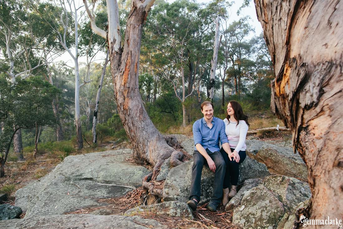 A great bush photo with the couple laughing a lot while sitting on a rock - Lake Parramatta