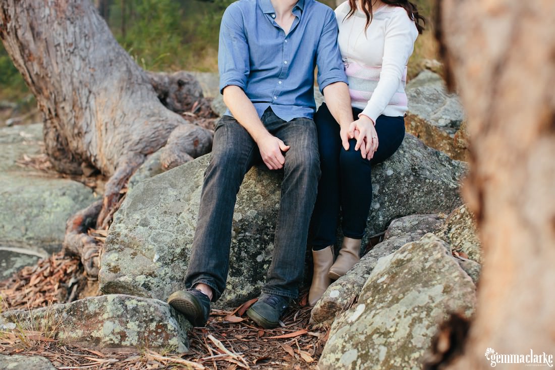 Close up photo of the couple touching hands whilst sitting on the rock. You cannot see their heads in this picture so it looks like quite an intimate moment - Lake Parramatta