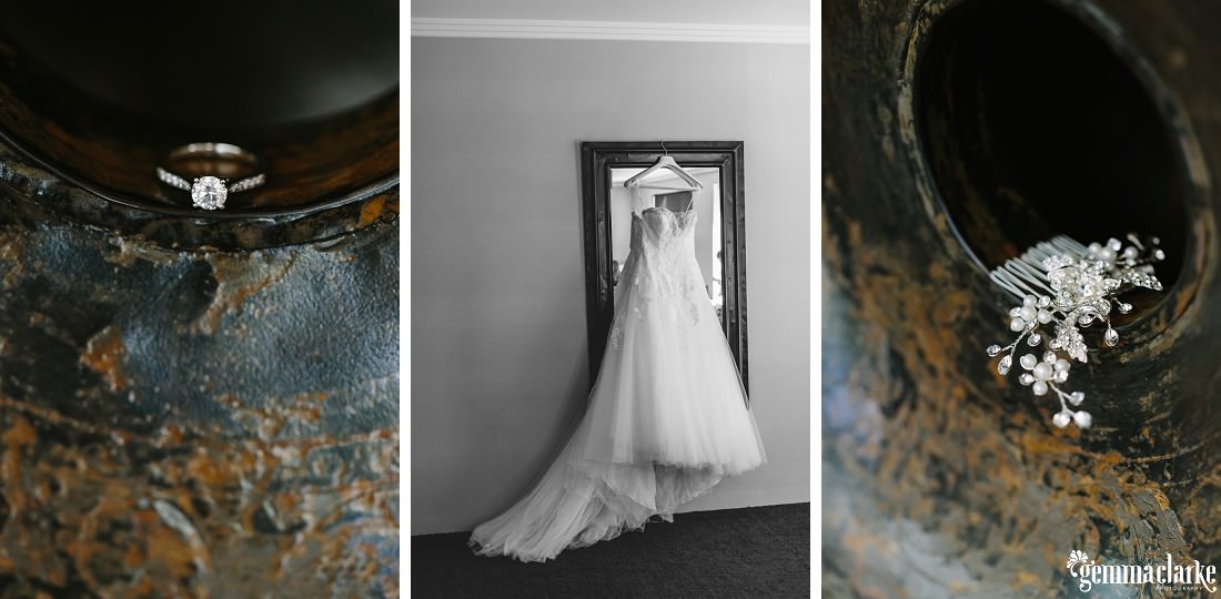 A bridal gown hanging in front of a mirror and some of a bride's accessories and ring