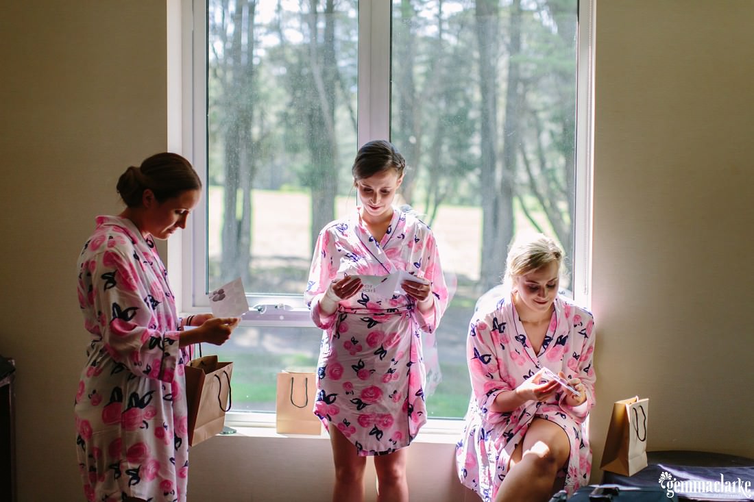 Bridesmaids in robes in front of a window ready cards