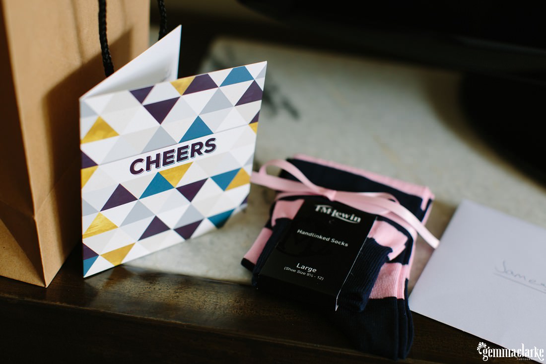 A "Cheers" card and a pair of socks tied with a pink ribbon