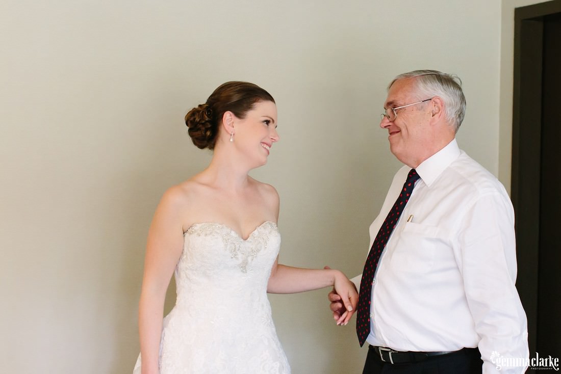 A bride and her father smiling at each other
