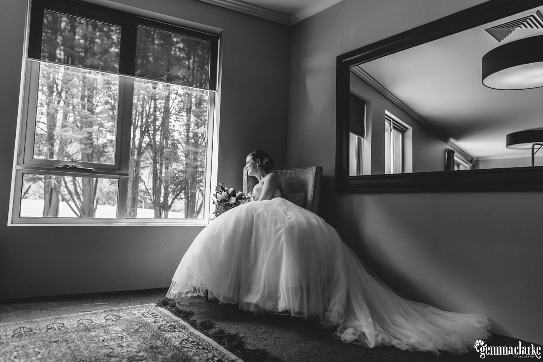 A smiling bride sitting on a chair by a window