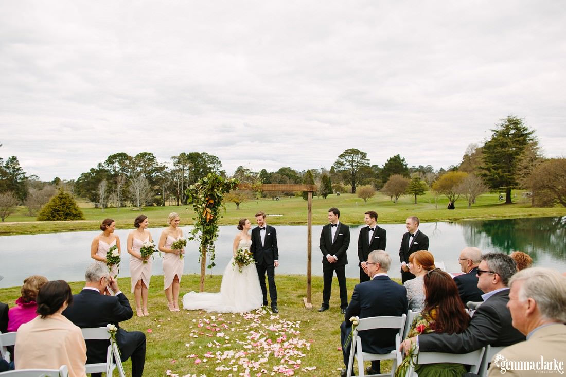 A wedding ceremony in progress in front of a small lake