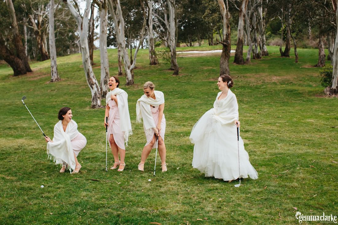 A bride and her bridesmaids posing with golf clubs