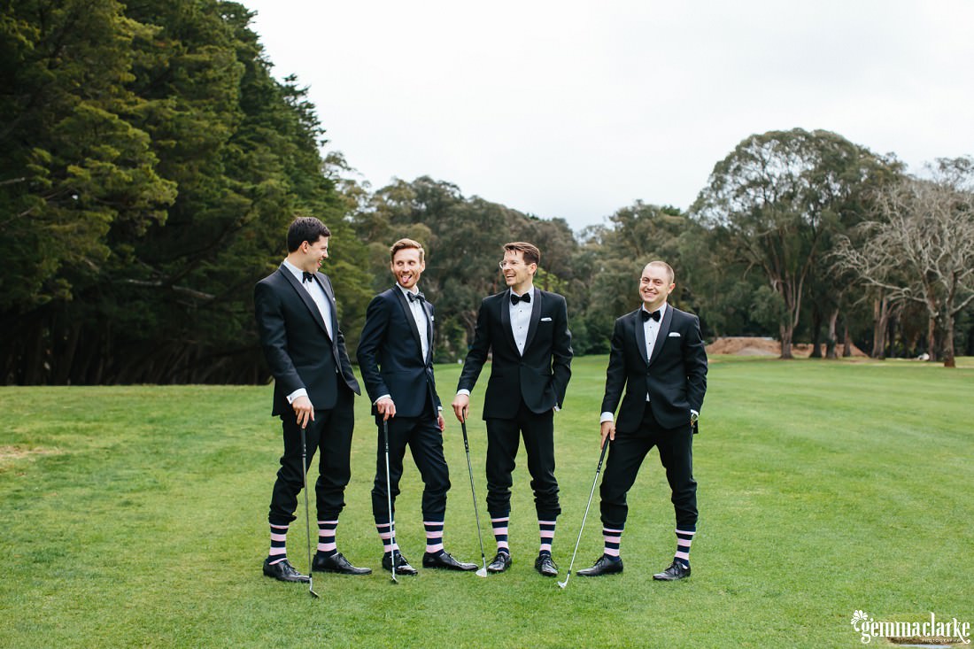 A groom and his groomsmen pose with golf clubs and show off their matching striped socks