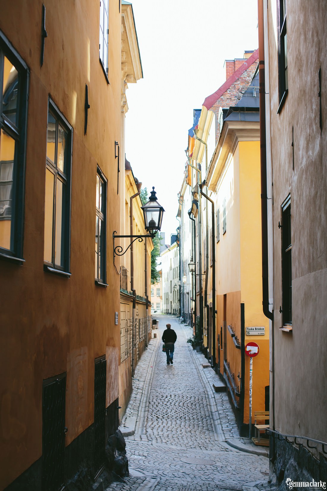 An early morning walk in an alley with golden buildings and cobblestone paths in Stockholm's Old Town, Gamla Stan