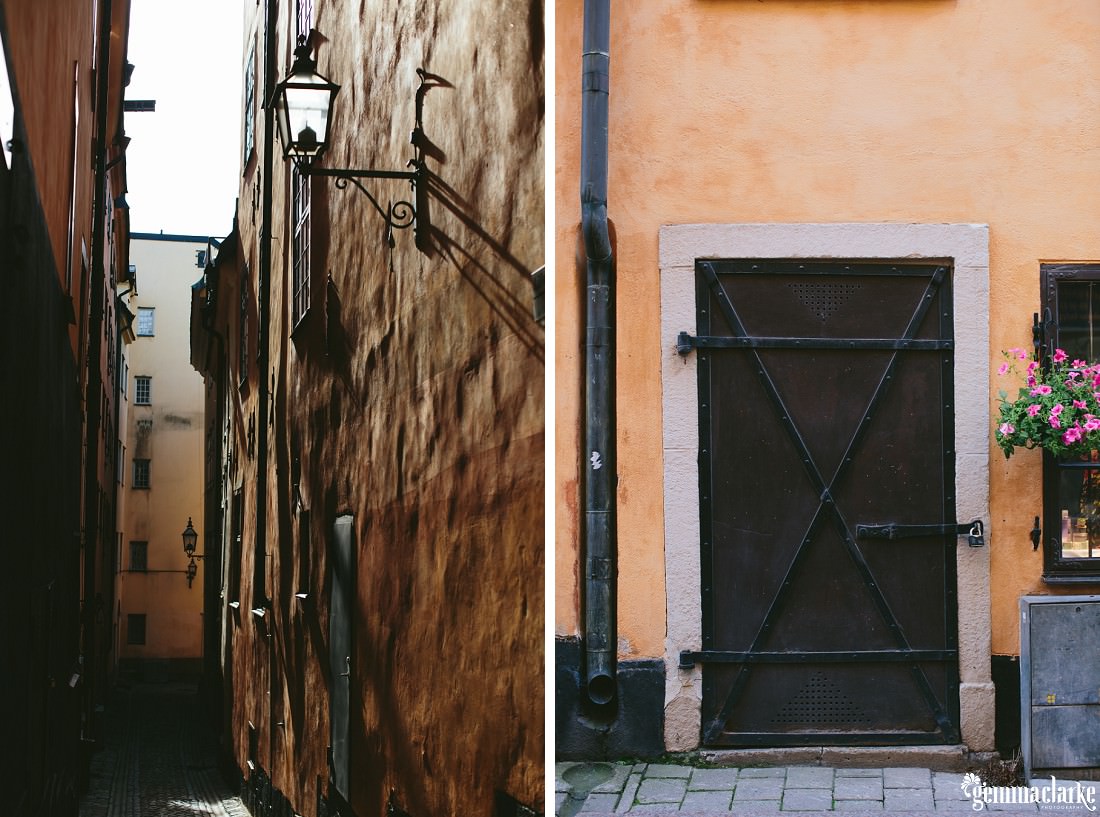 A view down an alley with black lamp and a golden wall with another view of a black iron door and flowers hanging beside in Stockholm's Old Town