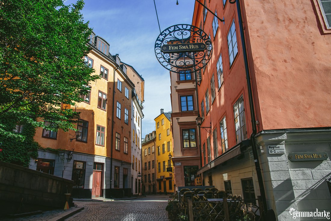 Colourful scene of buildings in Stockholm's Old Town with a big green tree on the left.